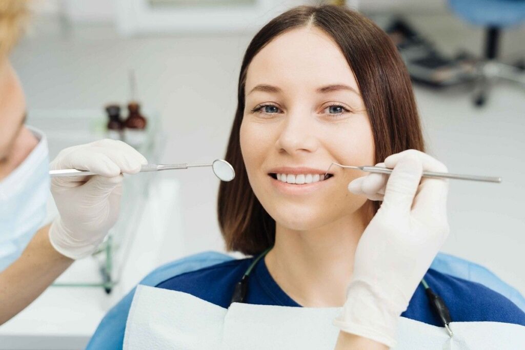 Dentist examining a smiling female patient during a routine dental exam in a modern dental office